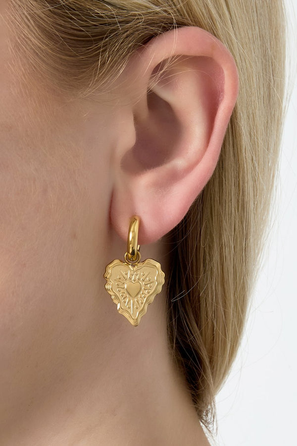 model draagt stainless steel hoop oorbellen met hartje hanger Mara Jewellery