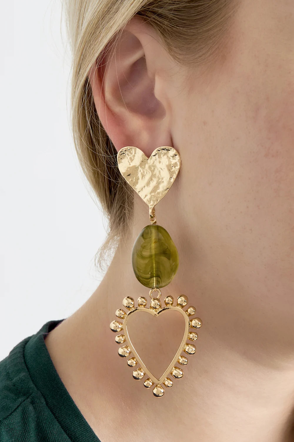 model draagt stainless steel oorbellen met hartjes en groene steen Mara Jewellery