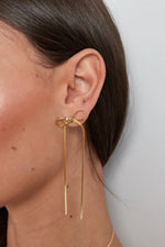 Load image into Gallery viewer, model draagt stainless steel oorbellen met strik en lange ketting Mara Jewellery
